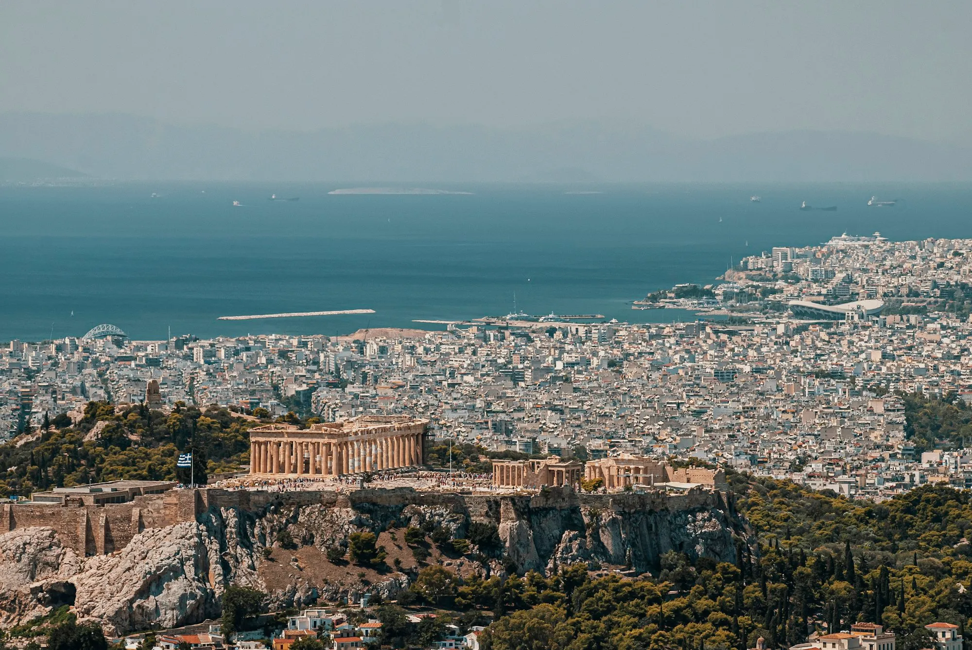 A Acrópole de Atenas vista do alto, com o rochedo do Areópago ao lado e o mar ao fundo