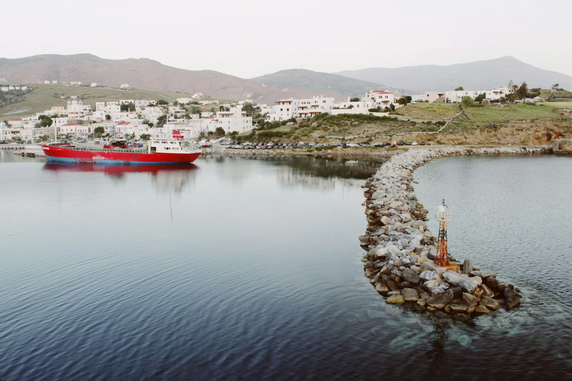 Ferry atracado no porto de uma ilha grega, com vilarejo de casas brancas ao fundo