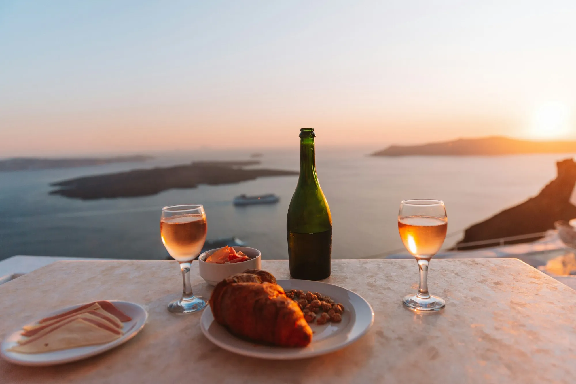 Jantar romântico com vinho ao pôr do sol à beira-mar na Grécia